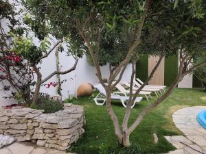a garden with a bench and trees and a stone wall at North Wind House in Peniche