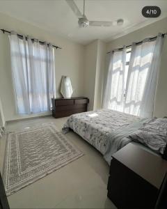 a bedroom with a bed and two windows and a rug at Bowsher 501 in Muscat