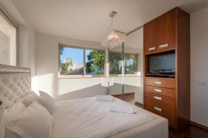 a bedroom with a bed and a tv and a window at Cosytal Villa in Herzliya