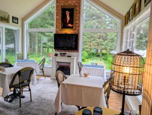 a dining room with tables and a fireplace and windows at La Tremblante in Mont-Tremblant