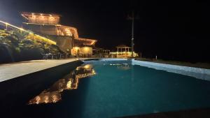 a swimming pool at night with a building in the background at Nature's Glory Resort in Panchgani +38 photos