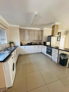 a large kitchen with white cabinets and a tile floor at Kairos Home in Maseru