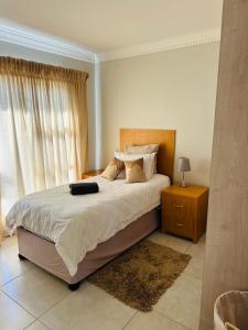 a bedroom with a large bed with a nightstand and a window at Kairos Home in Maseru