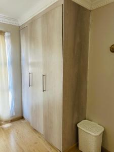 a large wooden cabinet in a room with a bench at Kairos Home in Maseru
