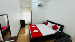 a bedroom with a red and white bed with a mirror at Athena Guest House in Trincomalee