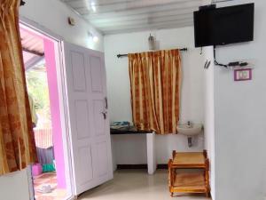 a room with a door and a sink and a television at S K S HOME STAYs in Vālpārai