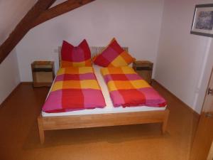 Una cama con mantas y almohadas coloridas. en Ferienwohnungen Schuh en Ipsheim