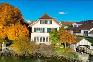 a large white house sitting next to a body of water at Lakefront Villa in Stäfa
