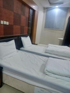 two beds in a room with white sheets at فندق علي عايض الدوسري in Abu Arish
