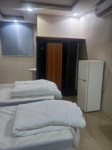 a room with three beds and a refrigerator at فندق علي عايض الدوسري in Abu Arish