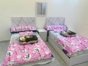 two beds in a room with pink comforters and pillows at Adamora Stay in Marsa Alam City