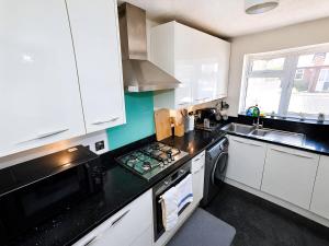 a kitchen with white cabinets and a black counter top at 2- Bed Contractor Home Near Heathrow in Feltham