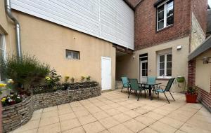 a patio with a table and chairs next to a building at L Ecureuil Ludique in Beaumont-le-Roger