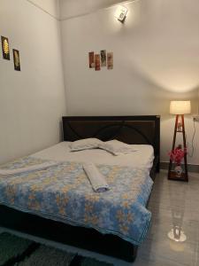 a bedroom with a bed and a lamp and a tripod at PINES and PETALS in Jorhat