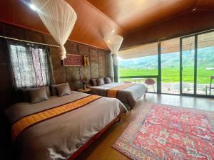 a bedroom with two beds and a large window at Stilla Home in Tả Van
