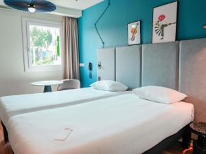 a bedroom with a large white bed with blue walls at ibis Martigues Centre in Martigues +127 photos