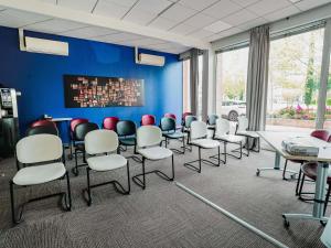 a room with chairs and tables in a room with blue walls at ibis Martigues Centre in Martigues