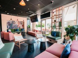 a lobby with pink and green furniture and windows at ibis Martigues Centre in Martigues