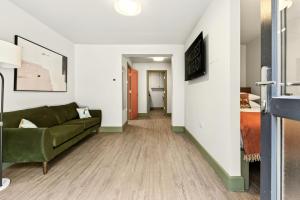 a living room with a green couch and a hallway at GuestReady - The Bridge - Wealdstone in London