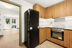 a kitchen with a black refrigerator and wooden cabinets at GuestReady - The Bridge - Wealdstone in London