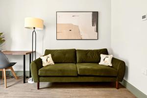 a green couch in a living room with a lamp at GuestReady - The Bridge - Wealdstone in London
