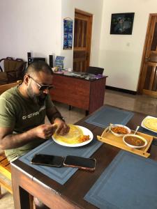 a man sitting at a table with a plate of food at Athena Guest House in Trincomalee