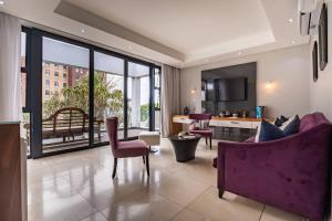 a living room with a purple couch and a kitchen at Isango Gate in Port Elizabeth