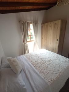 a bedroom with a white bed and a window at Villa Belén in Guarne +5 photos