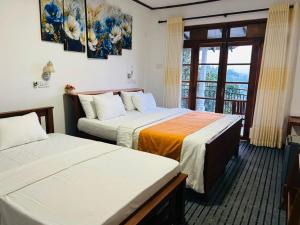 two beds in a room with a window at Okeed Ella in Ella