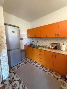 a kitchen with orange cabinets and a stainless steel refrigerator at Apartman Damir in Čeluga