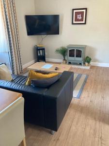 a living room with a black couch and a tv at Fairways in Cleveleys