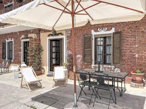 a table and chairs under an umbrella on a patio at Apartment Cà Maria-1 by Interhome in Asti