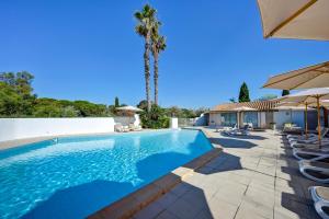 a pool with chairs and umbrellas next to a house at Les Rizières in Saintes-Maries-de-la-Mer