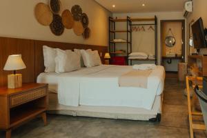 a bedroom with a large white bed and a desk at Pousada Moana in Fernando de Noronha