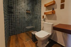 a bathroom with a toilet and a green tiled shower at Pousada Moana in Fernando de Noronha
