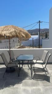 a patio with two chairs and a table and a straw umbrella at Aliki's Apartments in Vóthon