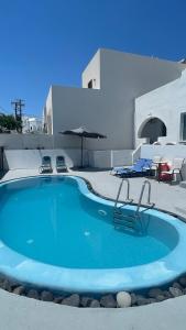 a large blue pool with chairs and an umbrella at Aliki's Apartments in Vóthon