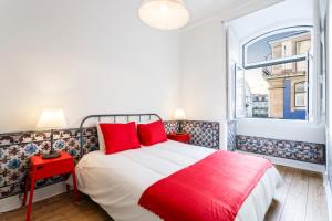 um quarto com uma cama com almofadas vermelhas e uma janela em WHome | Fanqueiros Downtown Typical Apartment em Lisboa