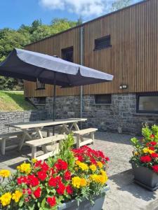 a picnic table with an umbrella and some flowers at Studio Le Vedeur in Durbuy