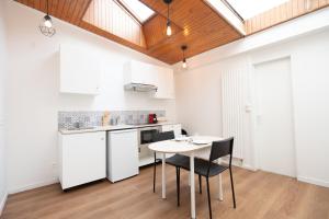 a kitchen with white cabinets and a table and chairs at T2 Cosy - Amiens Centre - Wifi in Amiens