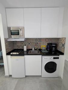 a kitchen with white cabinets and a sink and a microwave at Ocean View Studio in Playa del Ingles in San Bartolomé
