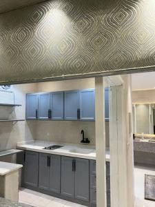 a kitchen with blue cabinets and a patterned ceiling at The Mountain View in Al Namas in Al Namas