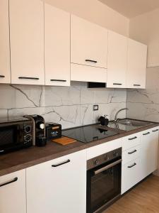 a kitchen with white cabinets and a microwave at Civico 44 in Castelmezzano +4 photos