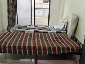 two beds in a room with a window at Shree Sai Ram PG in Pune