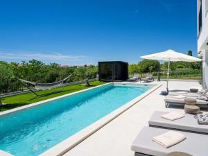 a swimming pool with chaise lounge chairs and an umbrella at Villa Loparia by Interhome in Lopar +65 photos