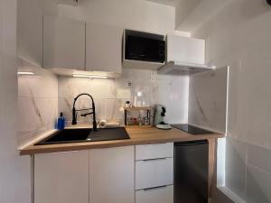 a white kitchen with a sink and a microwave at Chez Mel et Garry in Villedaigne +2 photos