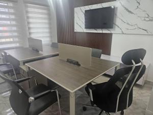 a meeting room with two desks with chairs and a tv at Soilsmart Haven in Abuja