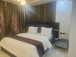 a bedroom with a large bed with white sheets and pillows at Soilsmart Haven in Abuja
