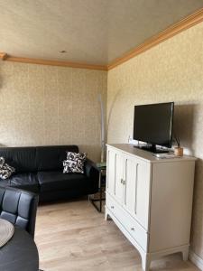 a living room with a couch and a tv on a cabinet at Het Kempens huisje in Lille