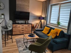 a living room with a blue couch and yellow pillows at Apartments Częstochowa - Nova Bursa - Prywatny parking! in Częstochowa